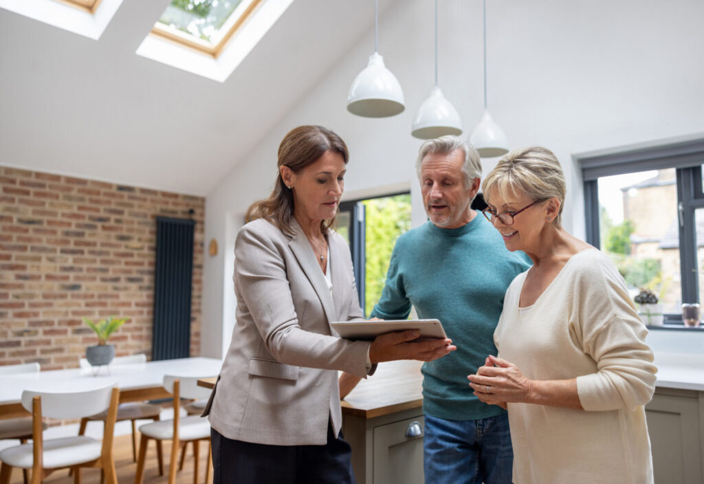 Real estate agent showing the blueprints of a house to a couple